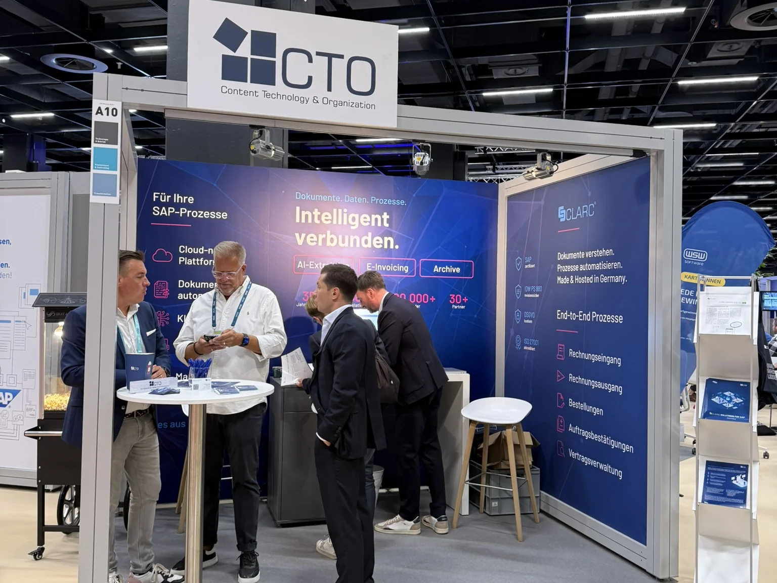 Fünf Personen in Gesprächen am CTO-Messestand A10, im Hintergrund die CLARC-Rückwand mit den Themen AI-Extraktion, E-Invoicing und Archive.