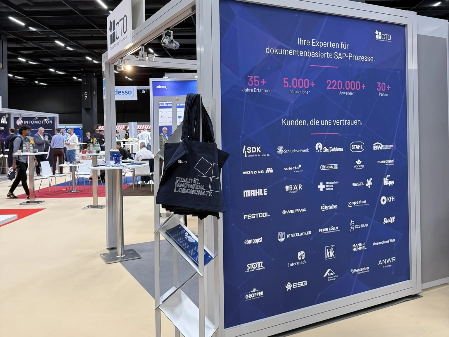 Rückwand des CTO-Messestands mit dem Titel „Ihre Experten für dokumentenbasierte SAP-Prozesse“, den Kennzahlen 35+ Jahre, 5.000+ Installationen, 220.000+ Anwender und 30+ Partner sowie Logos von Kunden wie MAHLE, Festool und MANN+HUMMEL.